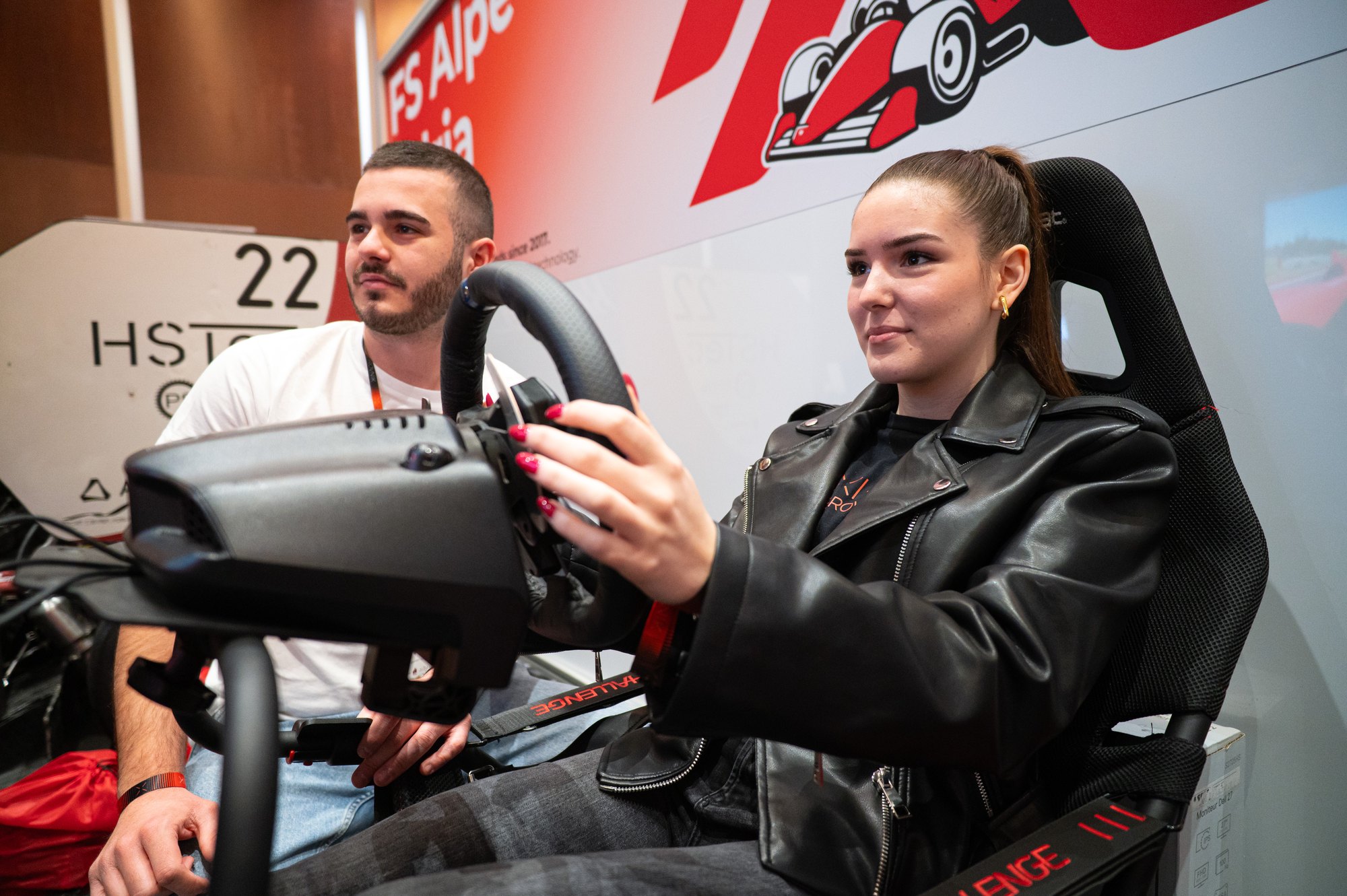 Posjetiteljica isprobava simulator vožnje uz pomoć domaćina.
